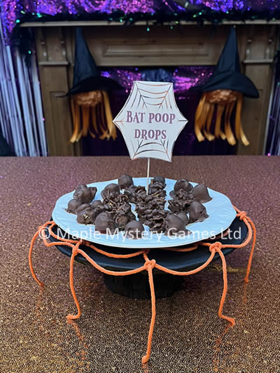 Cake stand is given a Halloween twist by covering it in black tissue paper and adding an orange spider's web