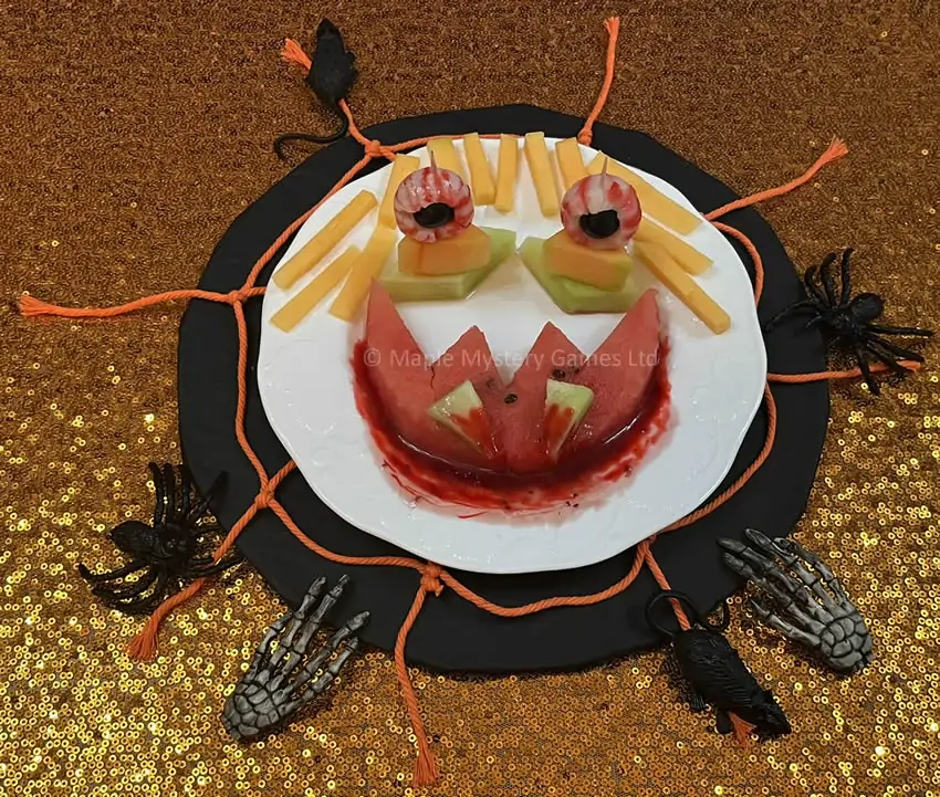 A Halloween face made out of melons, lychees and raspberry coulis with a small amount of red food coloring