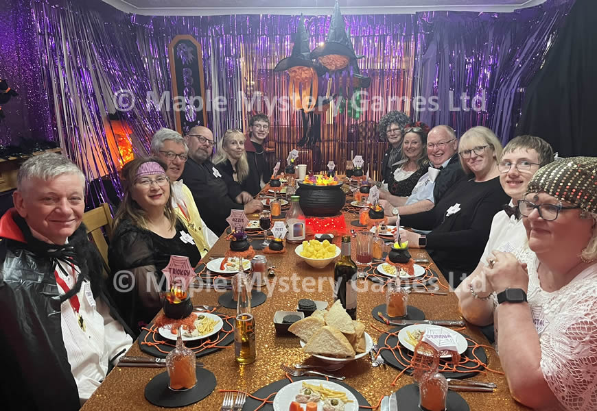 Guests at our Halloween murder mystery with cauldron in the center of the table and miniature cauldron place settings