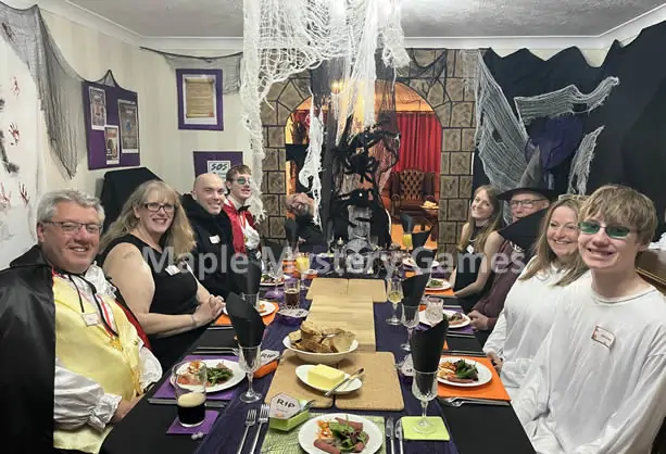 Our horror murder mystery party - photo shows guests at a dinner table decorated with cobwebs, coffins and giant spiders.