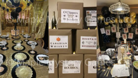 Speakeasy murder mystery party decorations: gold and black dining room; cardboard "crates" of moonshine; black and gold dining room